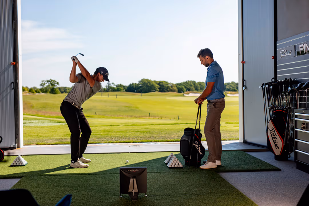 Golfer hitting in a fitting studio with a Trackman launch monitor